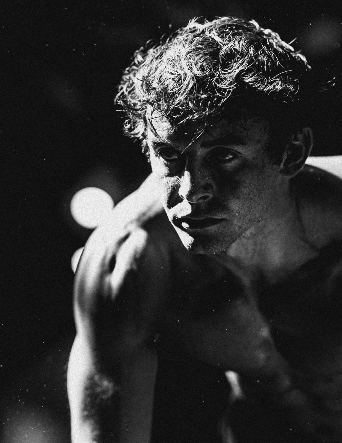 Anthony in black and white, head low, catching his breath in the dark