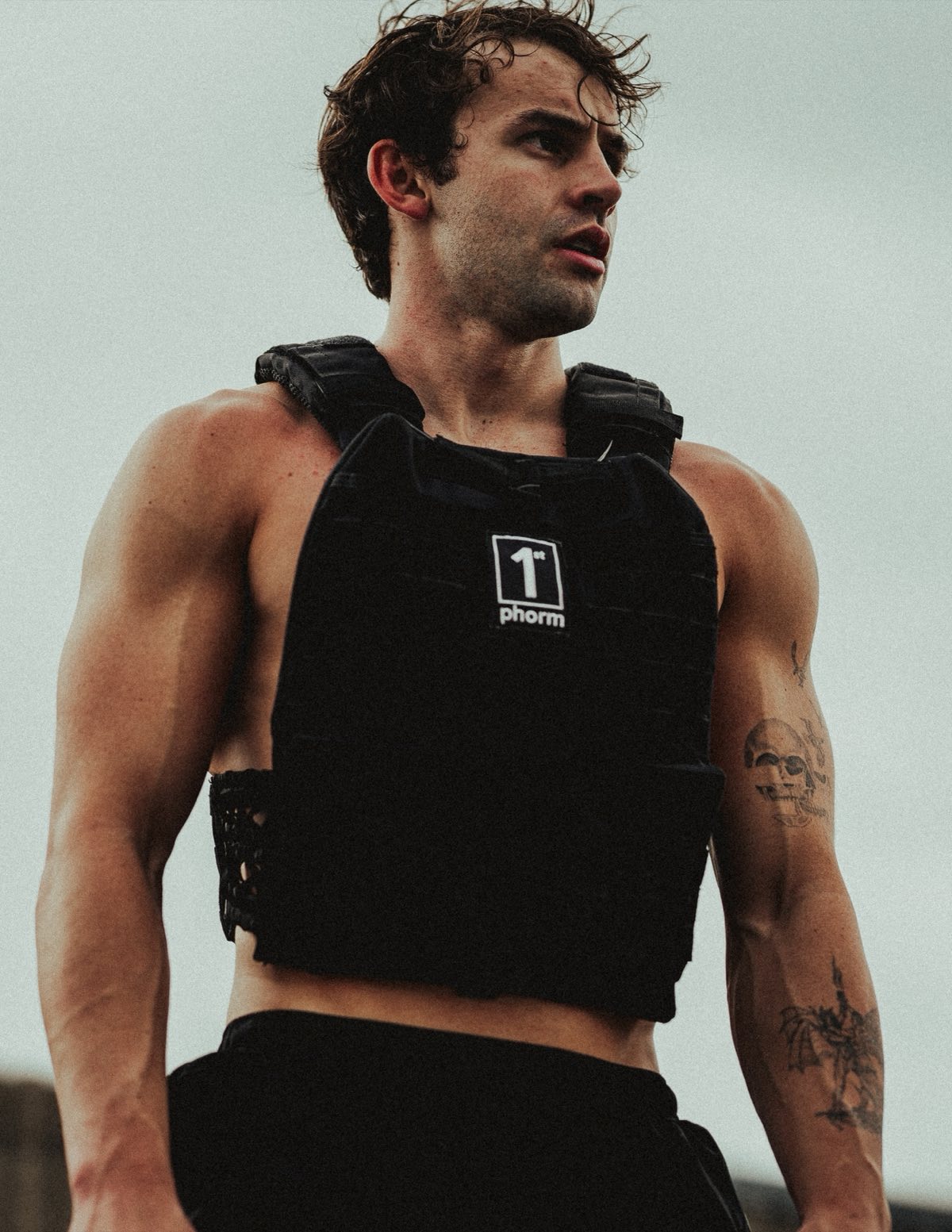 Anthony outdoors in a weighted vest, looking off to the side under a grey sky